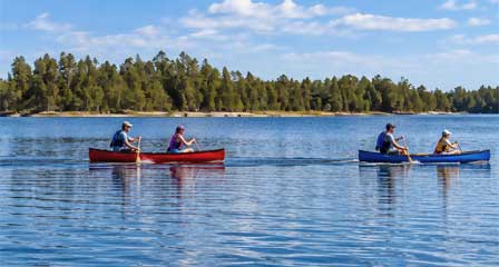 Two canoes paddling across Willow Springs Lake near Payson Arizona with ponderosa pines along the shoreline